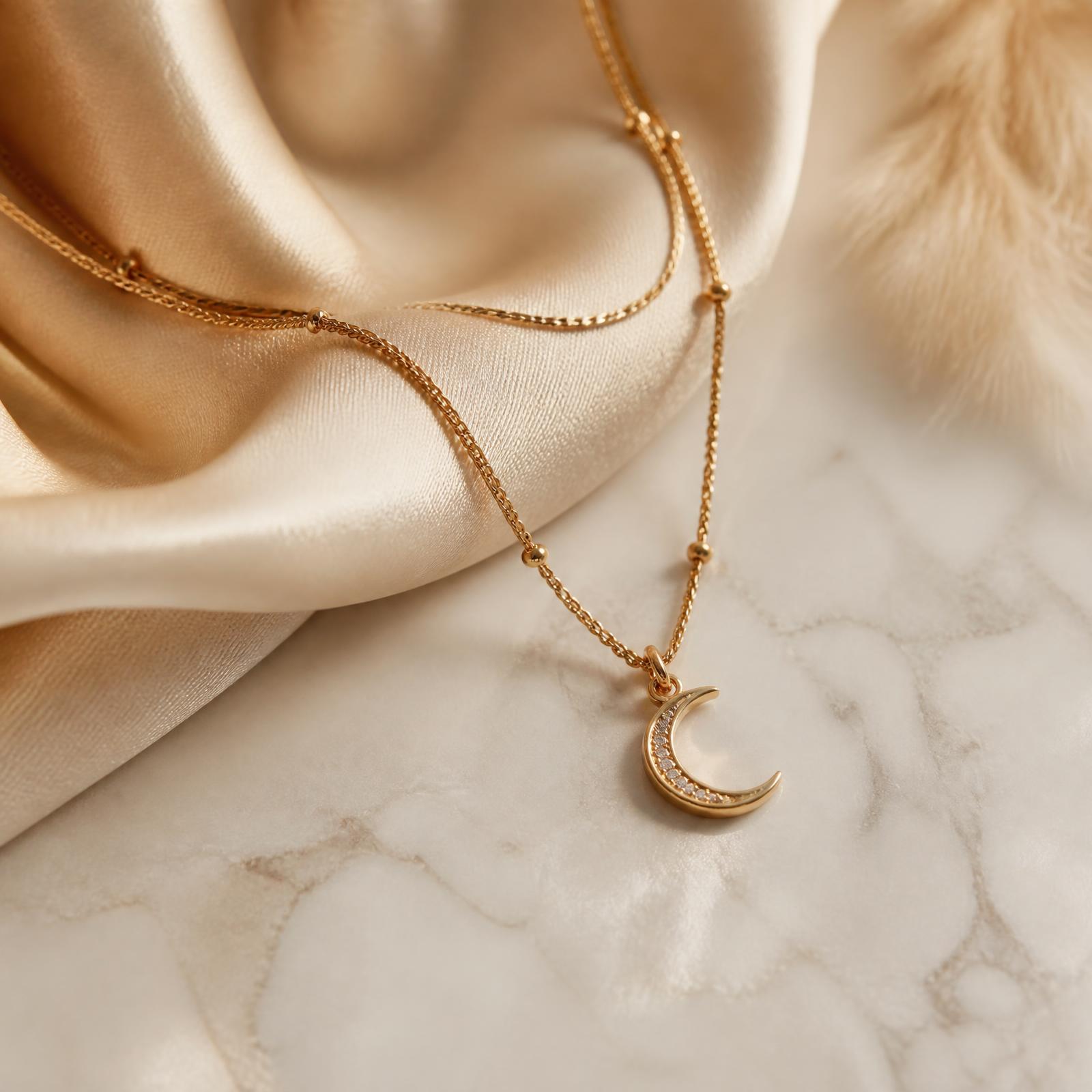 Colar dourado com pingente de lua sobre seda cor de champanhe